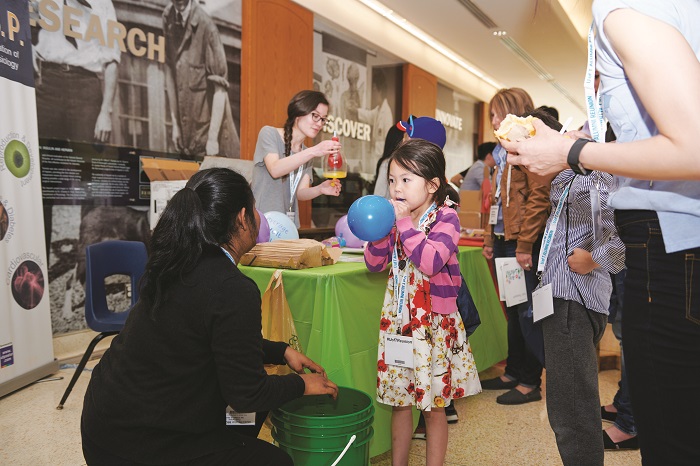 Young girl blowing up a balloon as part of a science experiment. Making learning fun at the Faculty of Medicine’s Kids’ Passport station. Photo by Grayson Lee.