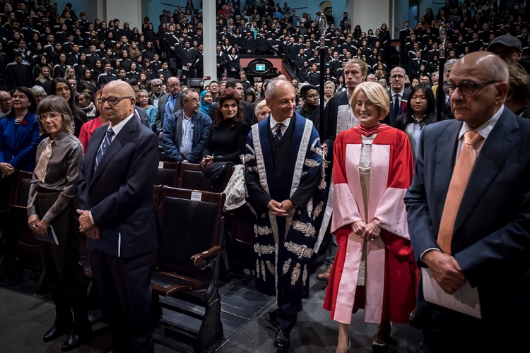 Rose Patten enters Convocation Hall with U of T President Meric Gertler in advance of the robing ceremony. Her husband Tom Di Giacomo is second from the left. Photo by Lisa Sakulensky.