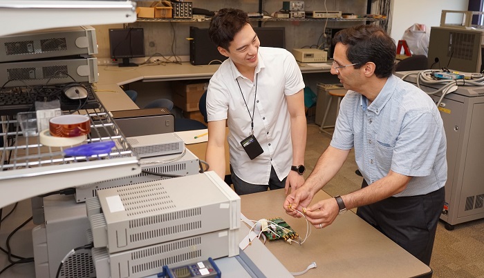 Professor Ali Sheikholeslami demonstrates the features of a test chip designed by his former PhD student Joshua Liang to his MASc student, Danny Yoo, in the lab (photo by Jessica MacInnis)