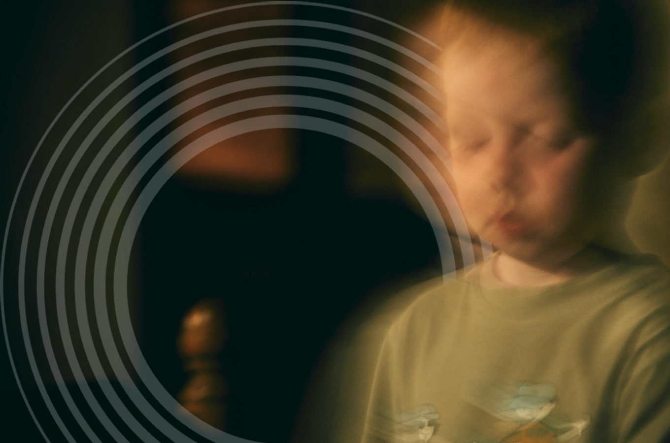 A toddler boy looks down with a serious expression. The image is subtly blurred and shaky.