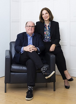 Donald A. Guloien and Irene Boychuk sit together in a big chair, smiling.