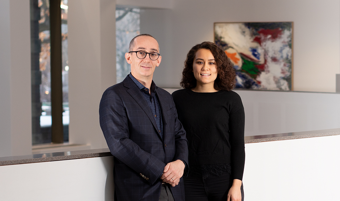 Jonathan Feldman and Alexandria Proctor, smiling in a building interior with a painting in the background.