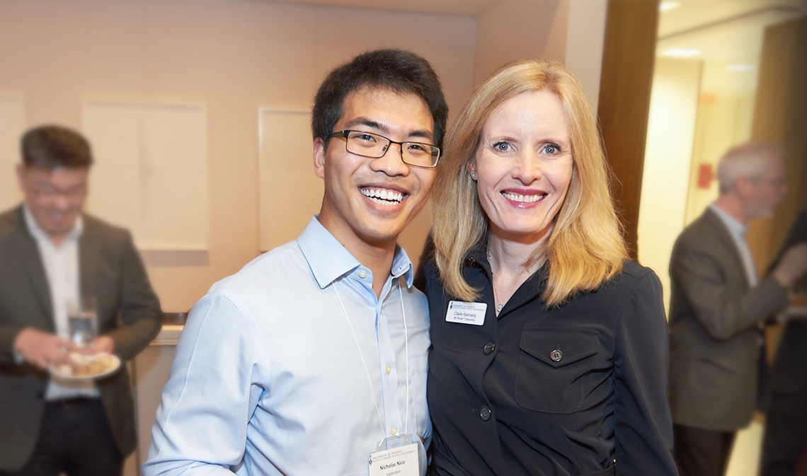 Claire Kennedy smiling with a student, at a reception indoors.