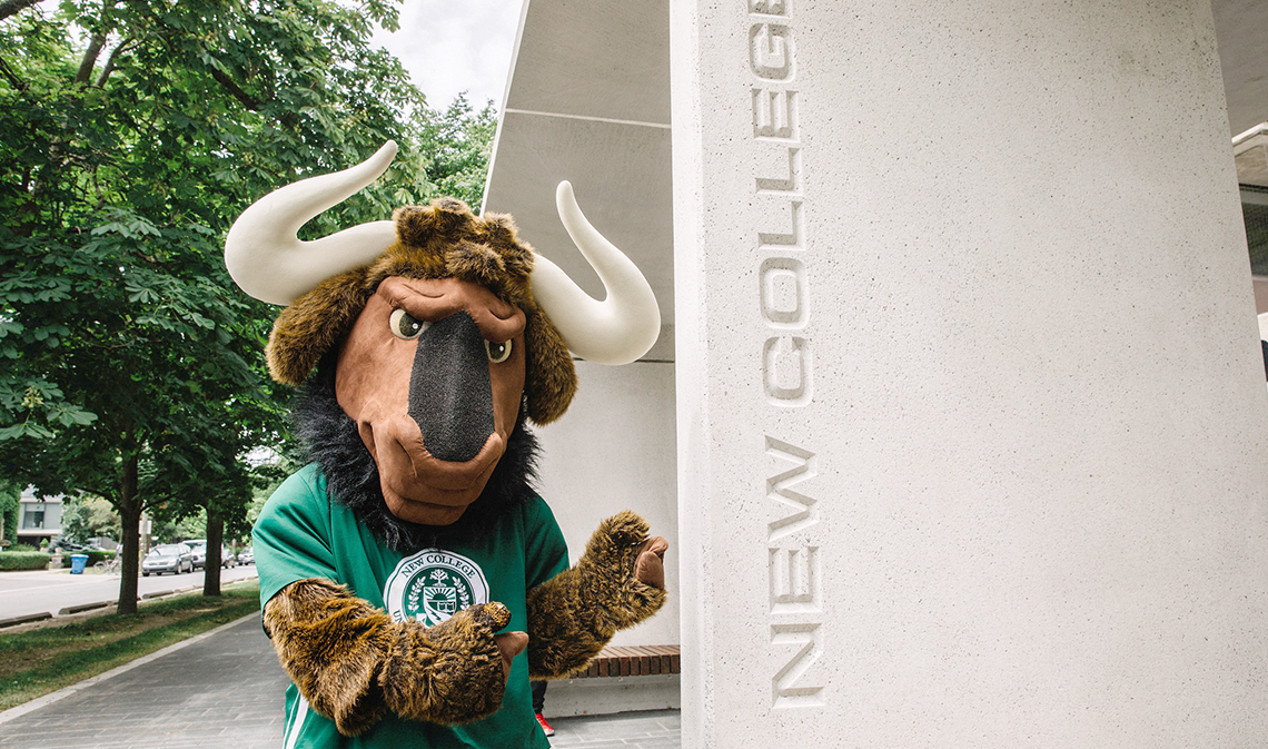 New College mascot Goliath the Gnu points to concrete plynth bearing name of New College.