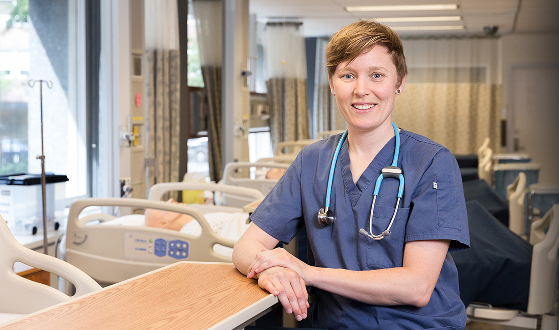 A nurse stands in front of a row of beds at the nursing simulation lab.