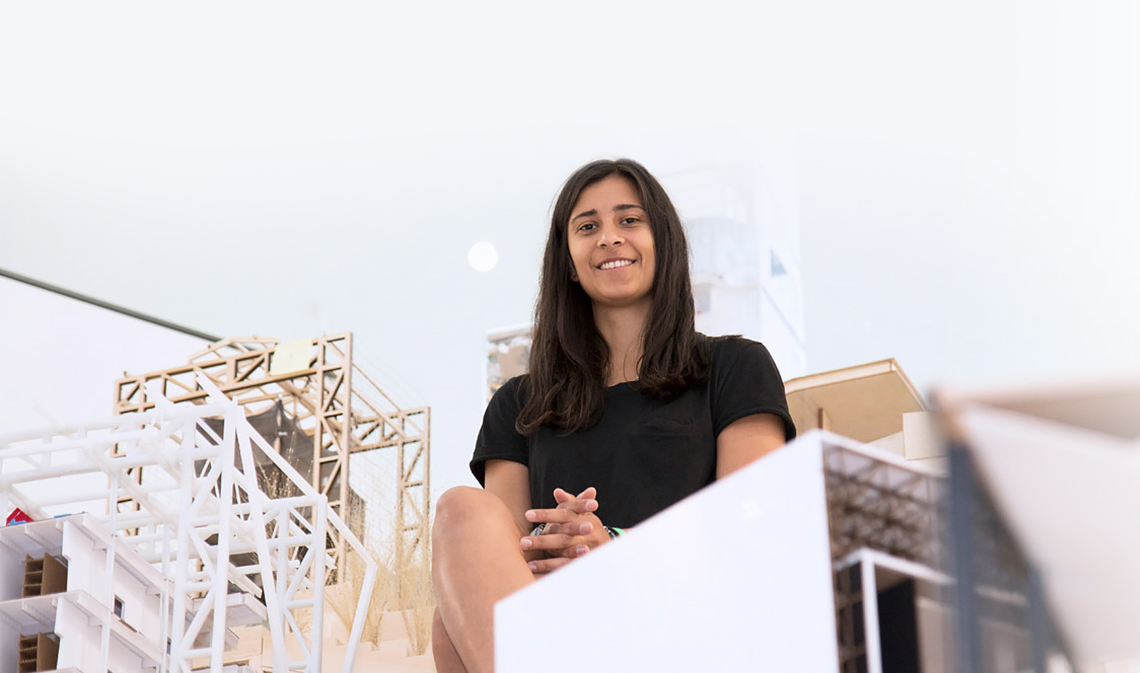 Shalice Coutu seated and smiling surrounded by architectural models.