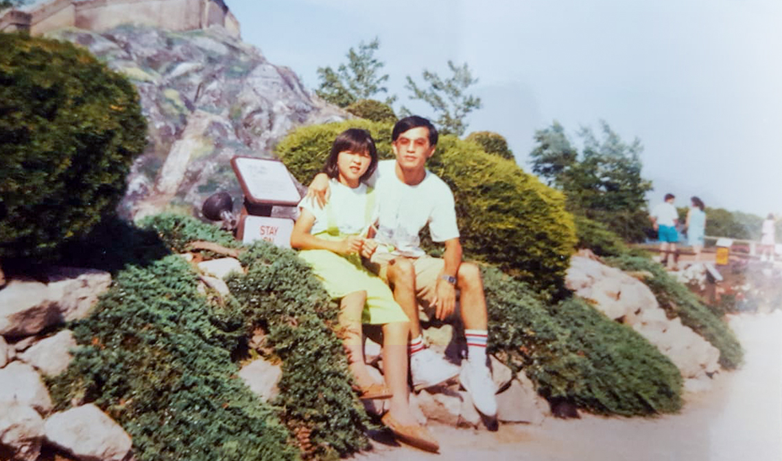 Vicky Nguyen (left) with her uncle Phu Hoang pictured in 1992, sitting outdoors on a sunny day.